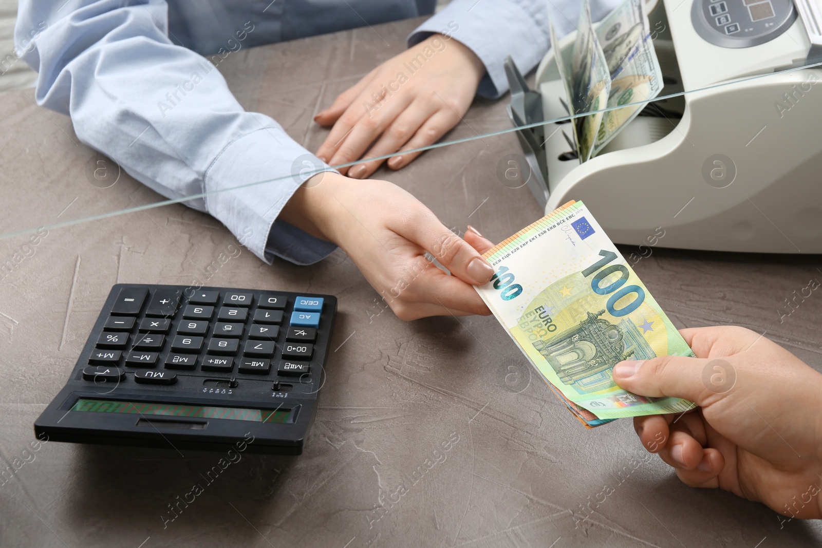 Photo of Client giving euro banknotes to cashier at table in money exchange, closeup