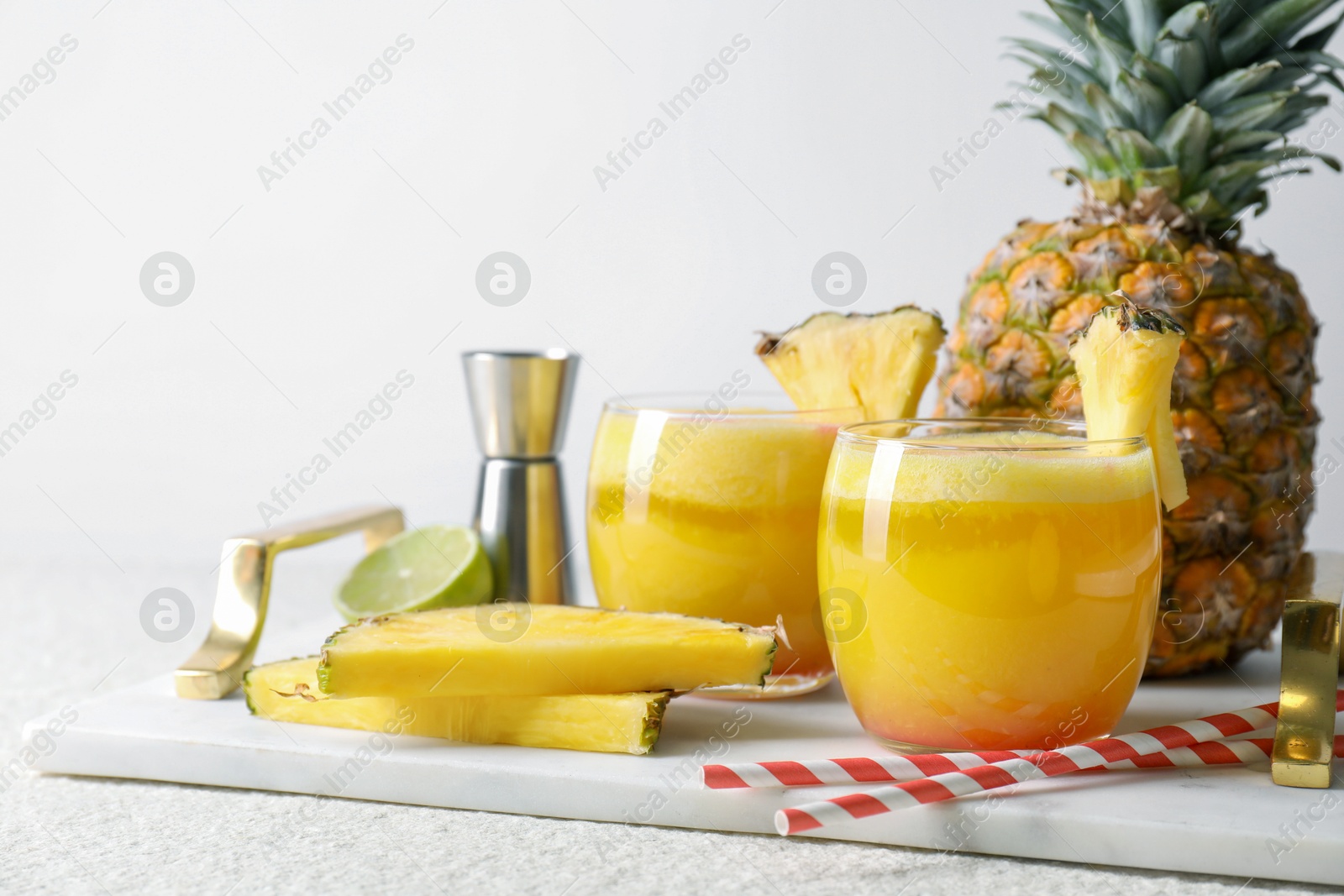 Photo of Tasty pineapple cocktail in glasses served on white table