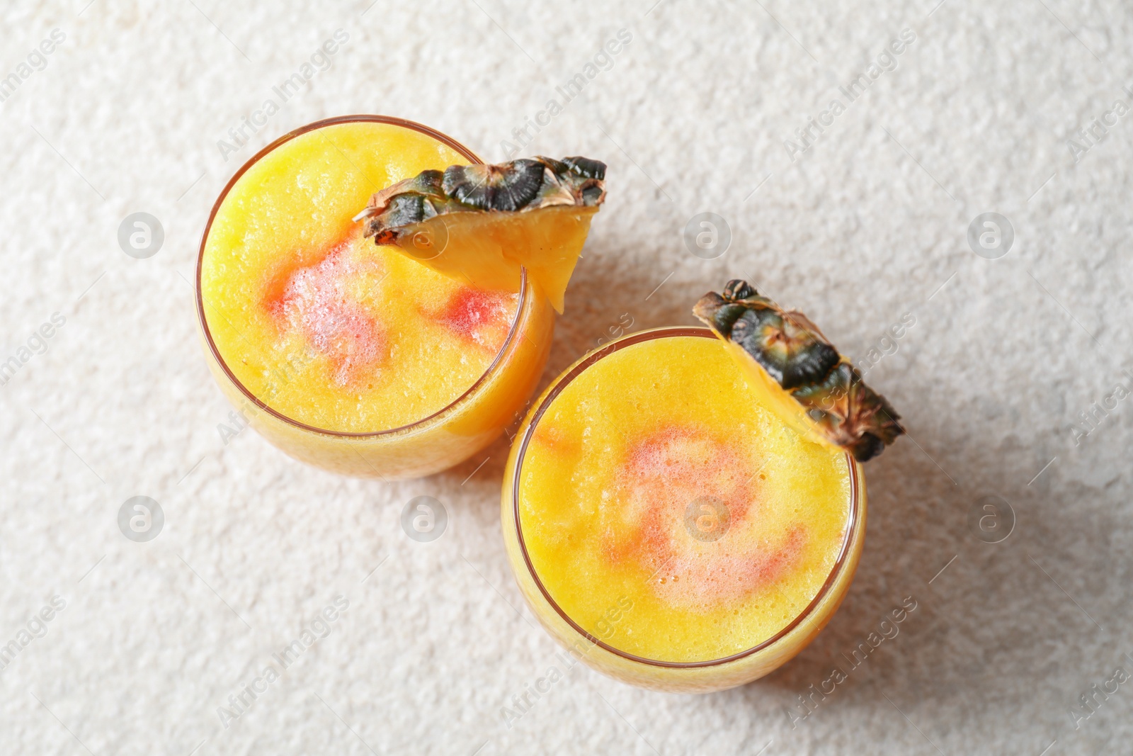 Photo of Tasty pineapple cocktail in glasses served on white table, top view