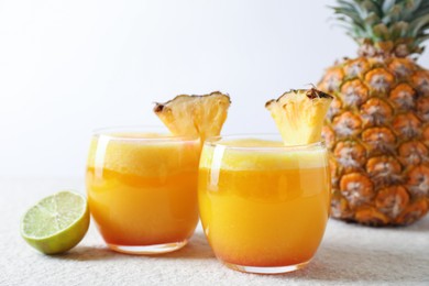 Photo of Tasty pineapple cocktail in glasses served on white table