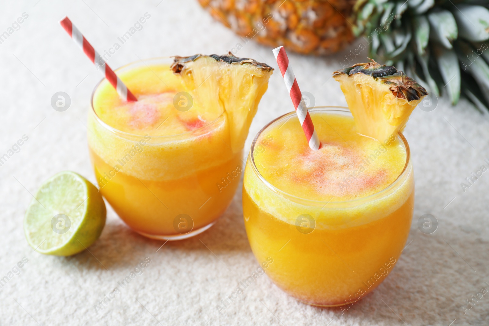 Photo of Tasty pineapple cocktail in glasses served on white table