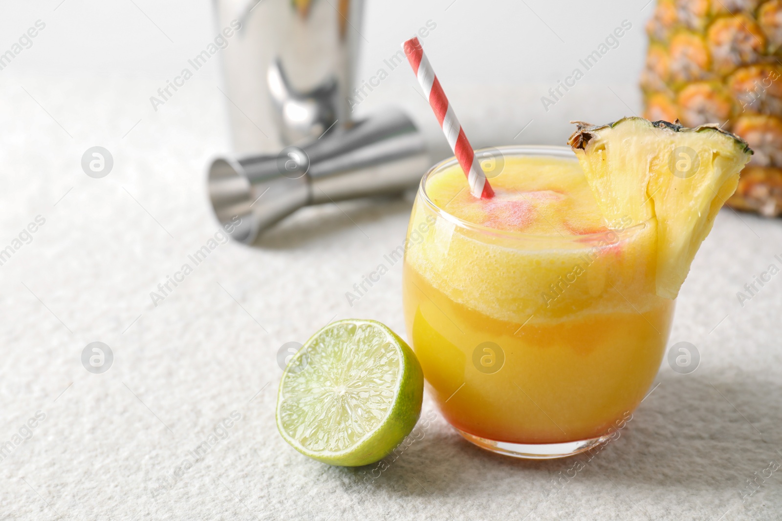 Photo of Tasty pineapple cocktail in glass served on white table, space for text