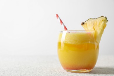 Photo of Tasty pineapple cocktail in glass served on white table, space for text