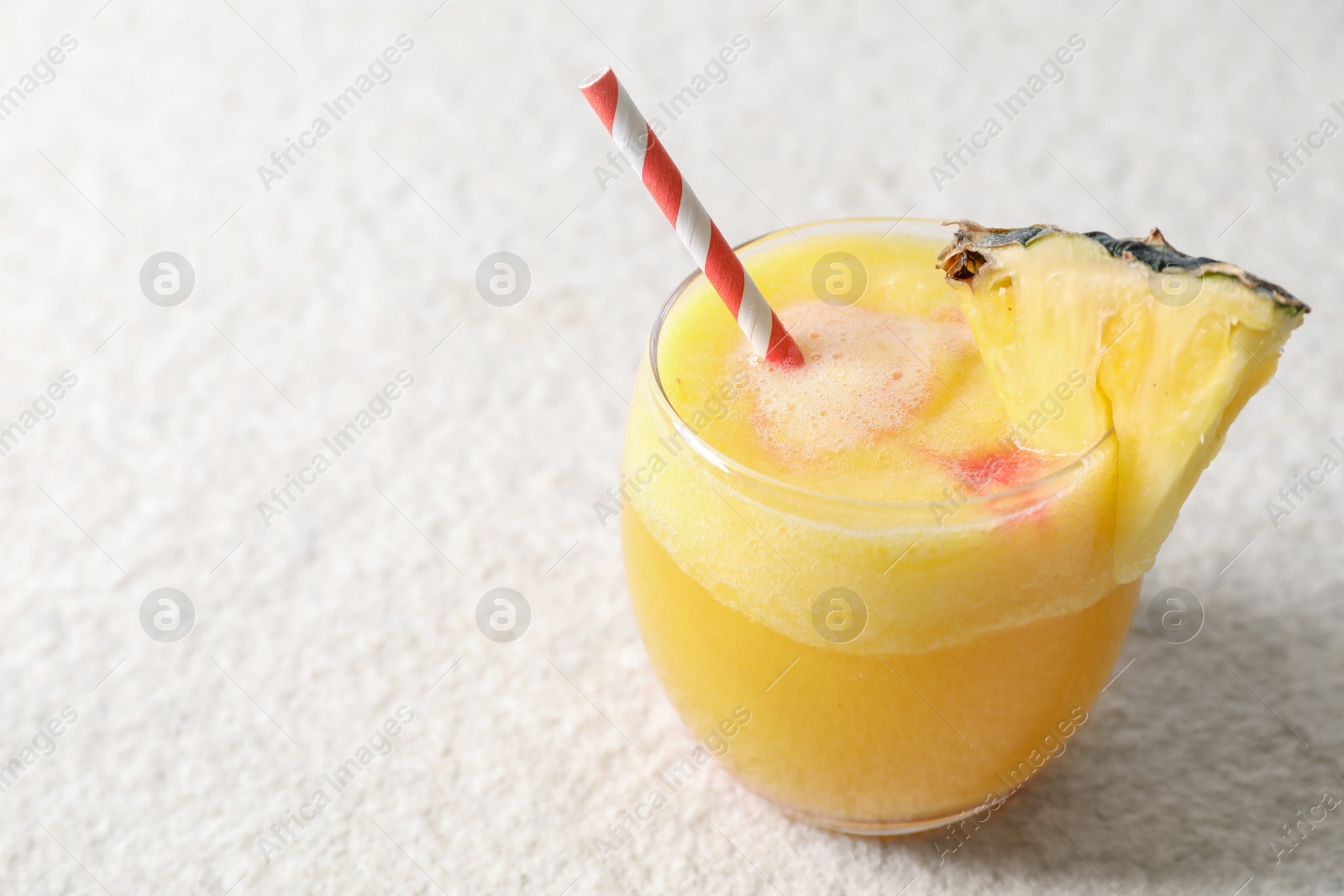 Photo of Tasty pineapple cocktail in glass served on white table, space for text