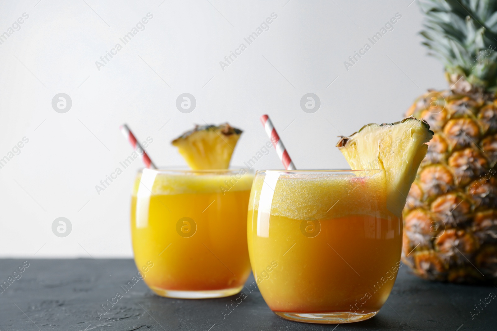 Photo of Tasty pineapple cocktail in glasses served on black table