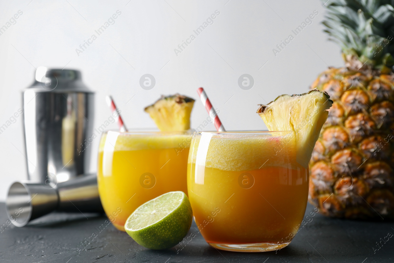 Photo of Tasty pineapple cocktail in glasses served on black table