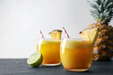 Photo of Tasty pineapple cocktail in glasses served on black table