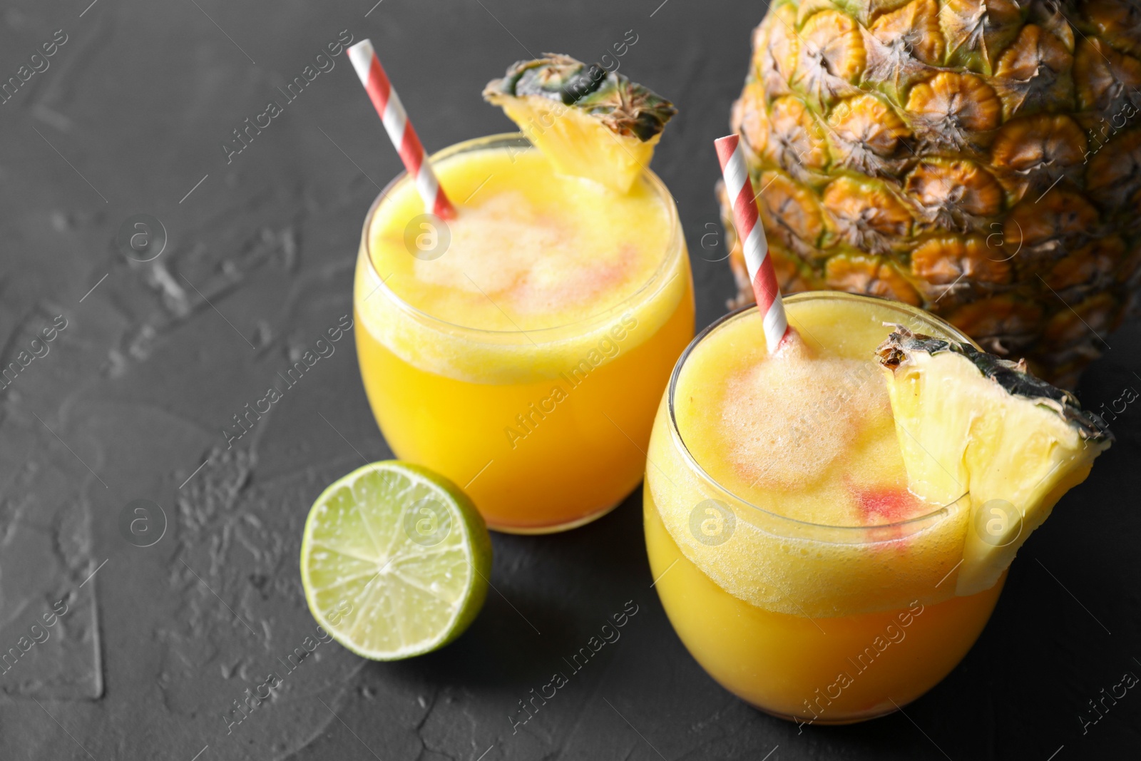 Photo of Tasty pineapple cocktail in glasses served on black table