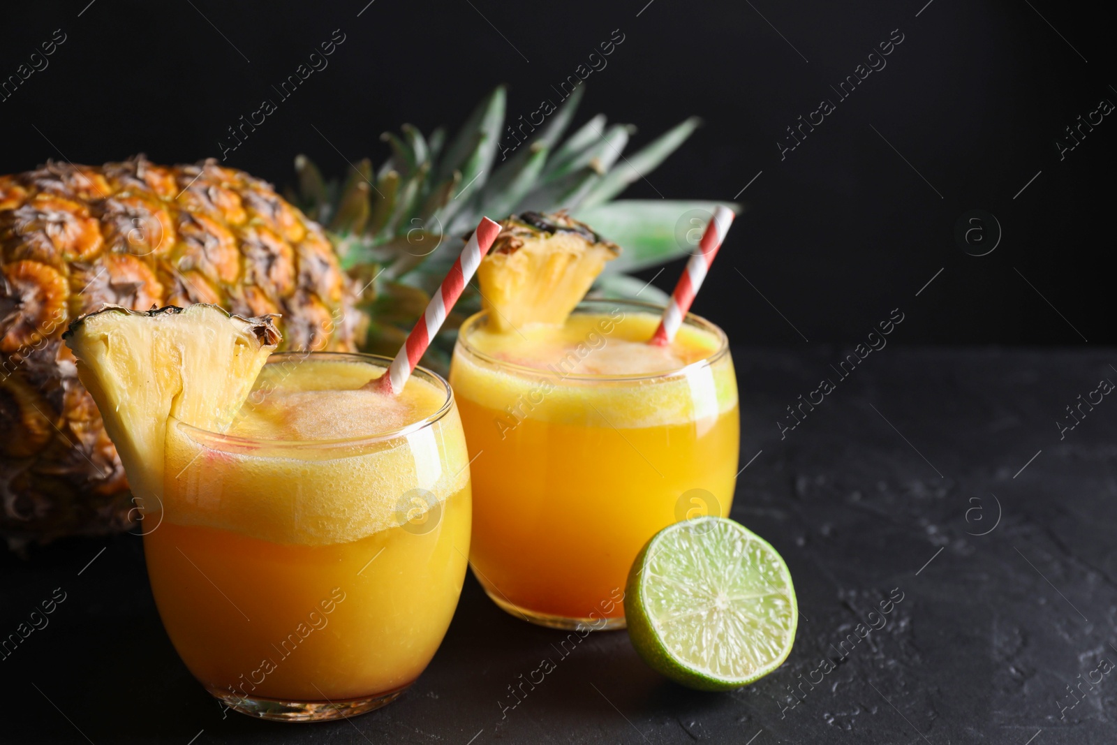 Photo of Tasty pineapple cocktail in glasses served on black table