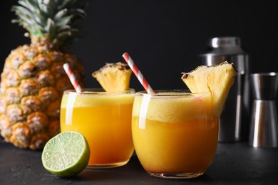 Photo of Tasty pineapple cocktail in glasses served on black table