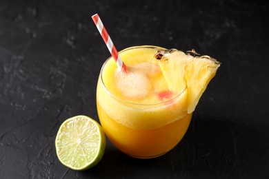 Photo of Tasty pineapple cocktail in glass served on black table, closeup