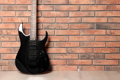 One modern electric guitar near brick wall. Space for text