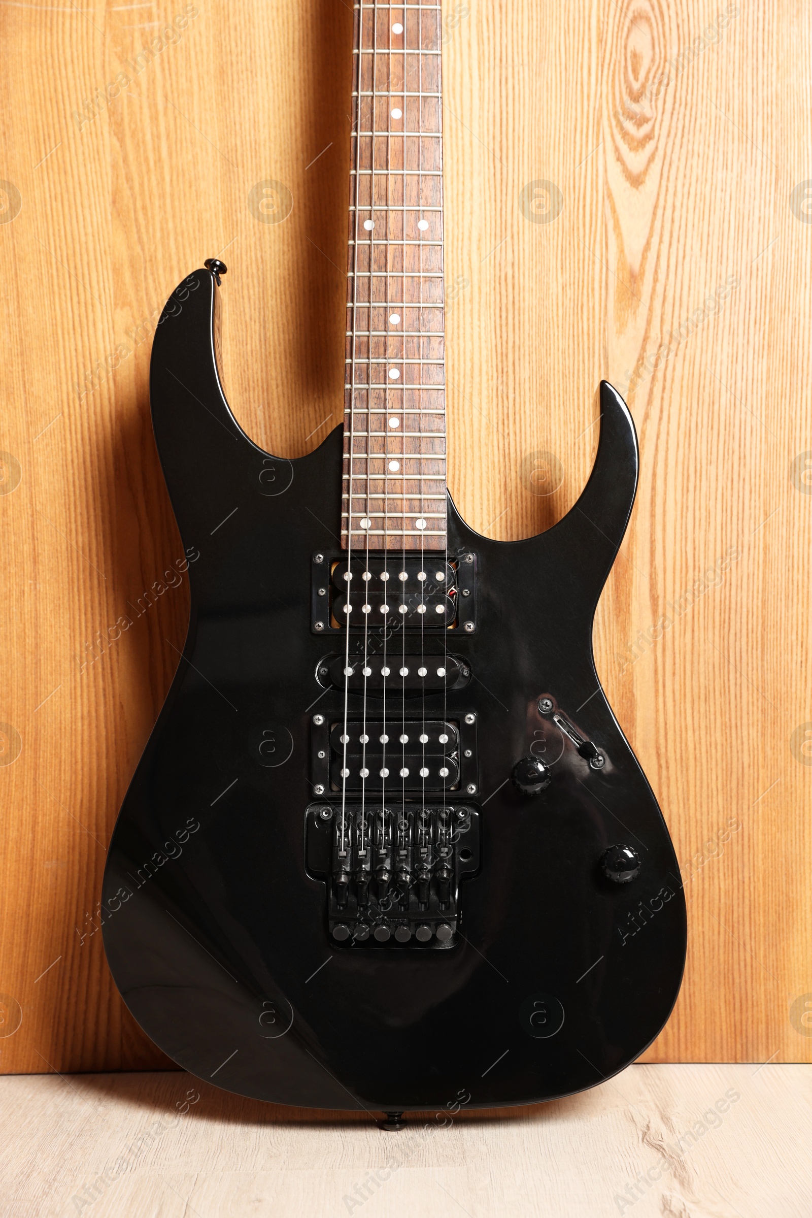 Photo of One modern electric guitar near wooden wall