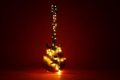 Photo of Electric guitar with Christmas lights on dark red background