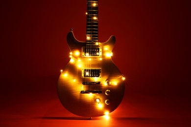 Photo of Electric guitar with Christmas lights on dark red background