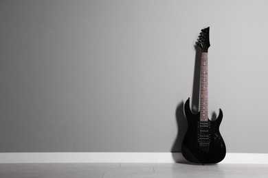 Photo of One modern electric guitar near light grey wall. Space for text