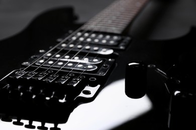 Photo of Modern electric guitar on black background, closeup