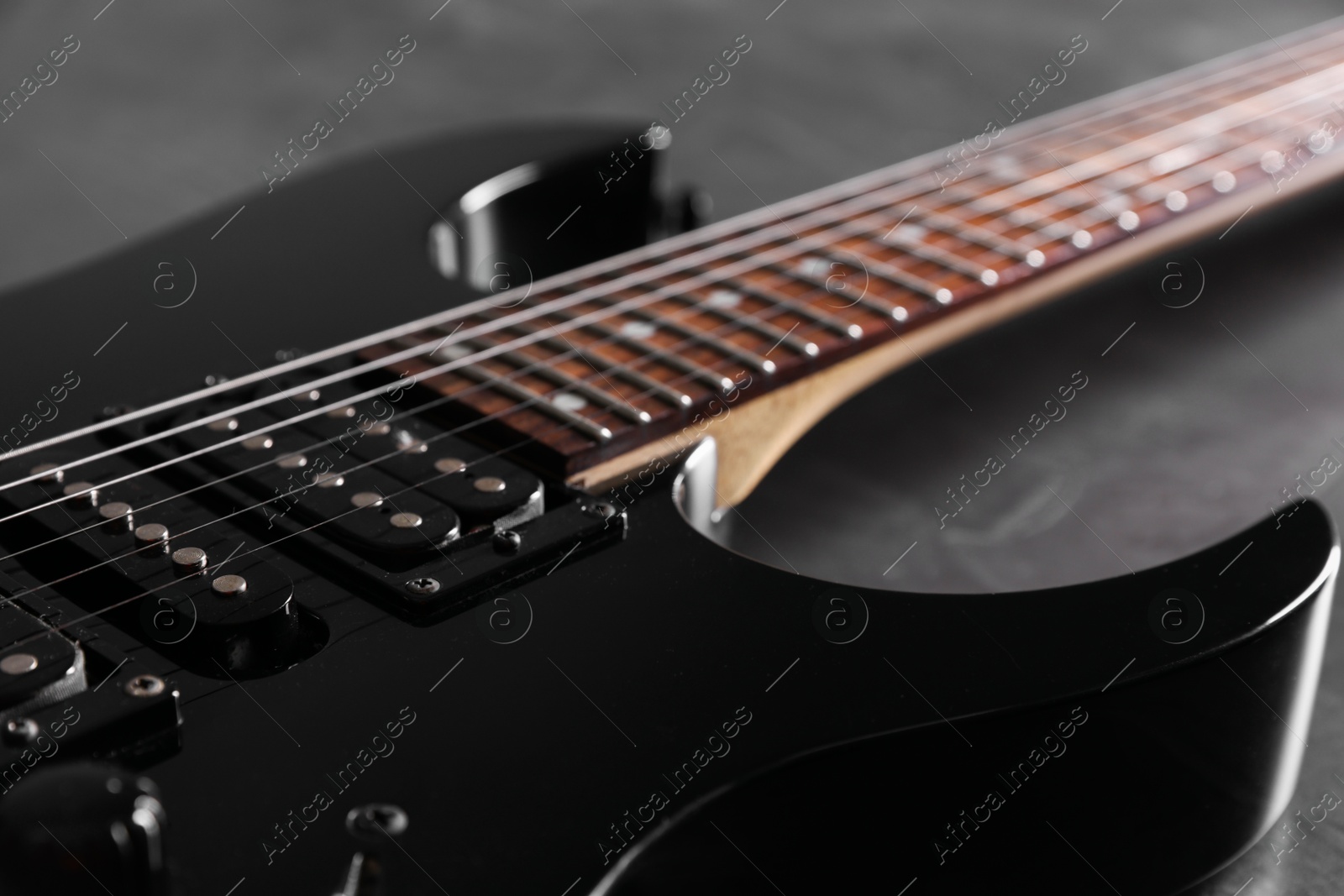 Photo of Modern electric guitar on black background, closeup