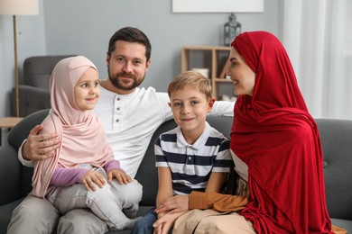 Photo of Happy Muslim family sitting on sofa at home