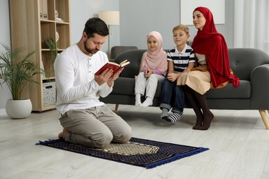 Happy Muslim family spending time together and praying at home