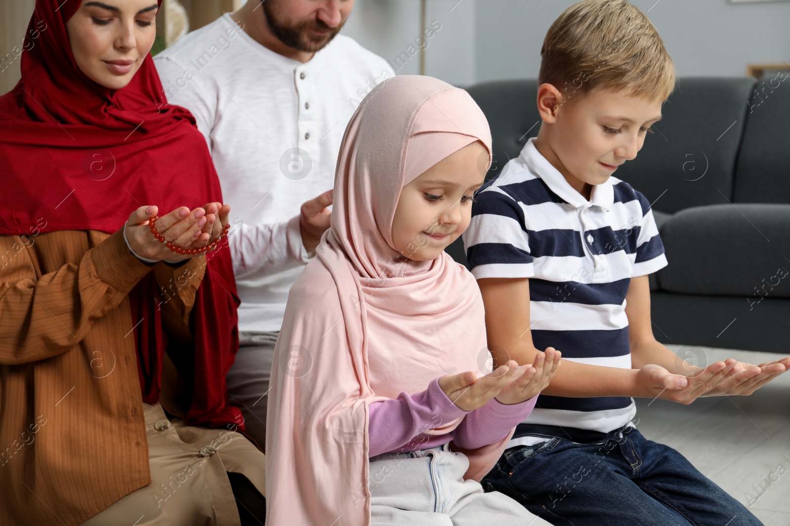 Photo of Happy Muslim family praying together at home