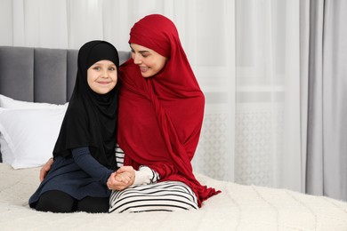 Photo of Muslim woman and her daughter spending time together at home, space for text