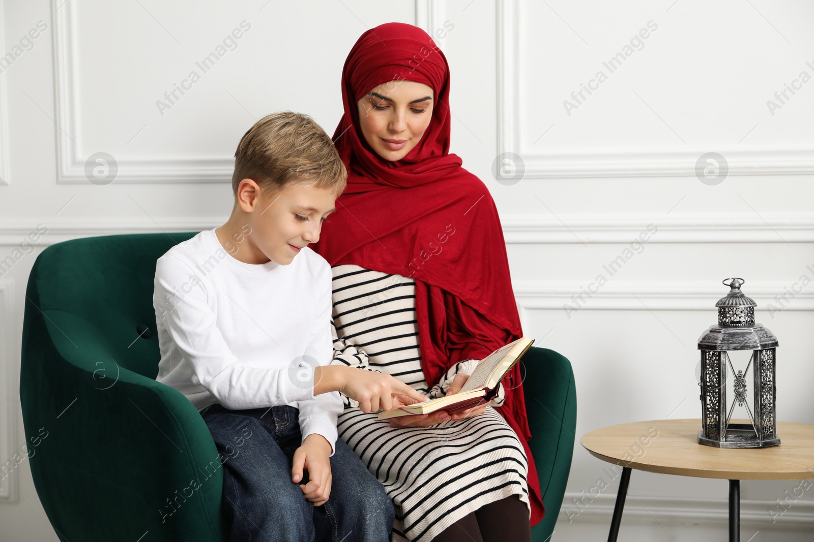 Photo of Muslim woman and her son reading Quran at home