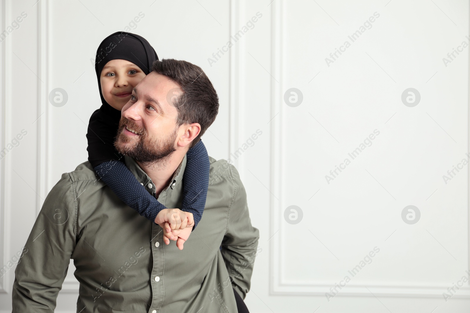 Photo of Muslim man and his daughter spending time together at home, space for text