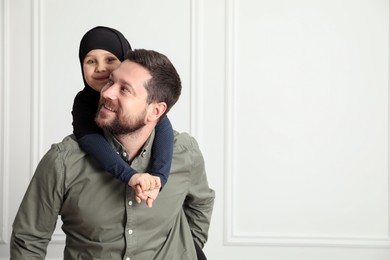 Photo of Muslim man and his daughter spending time together at home, space for text