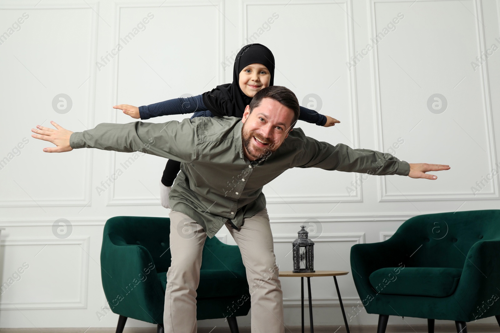 Photo of Muslim man and his daughter spending time together at home, low angle view