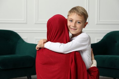 Photo of Muslim woman and her son spending time together at home