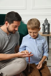 Muslim man and his son with prayer beads at home