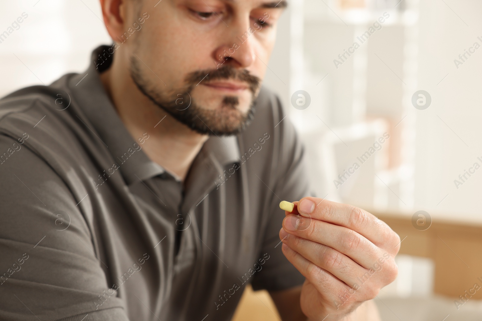 Photo of Man with pill at home, closeup on hand