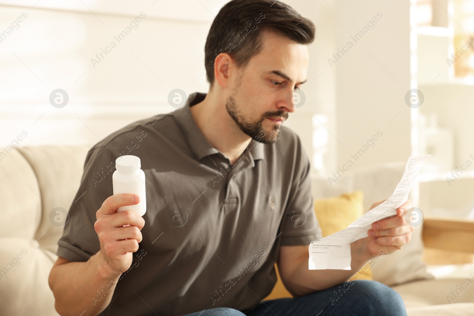 Photo of Man with pills reading instruction at home, selective focus