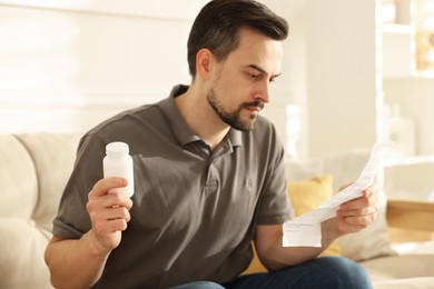 Photo of Man with pills reading instruction at home, selective focus