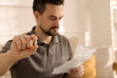 Photo of Man with pill reading instruction at home, selective focus