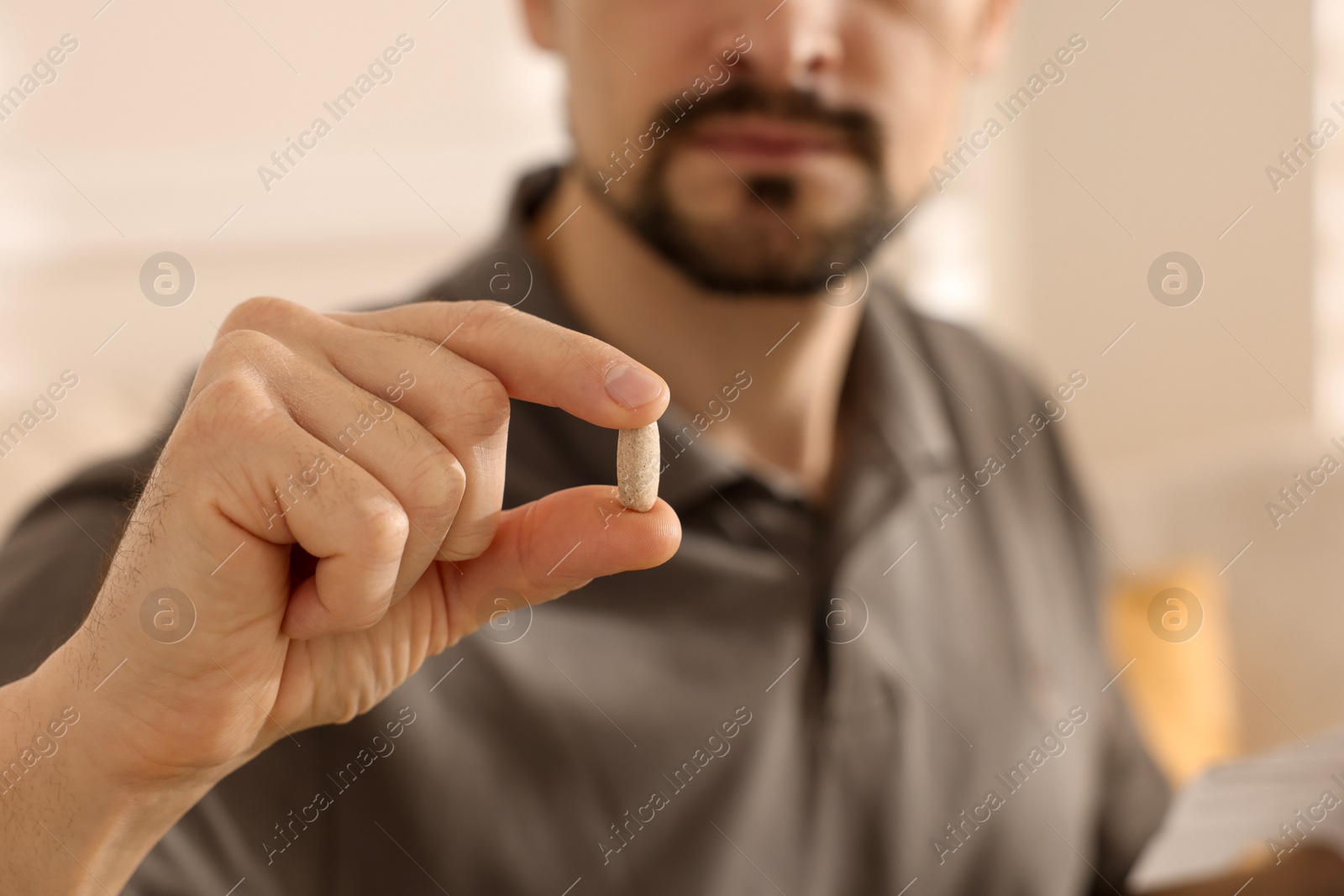 Photo of Man with pill at home, closeup on hand