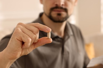 Man with pill at home, closeup on hand