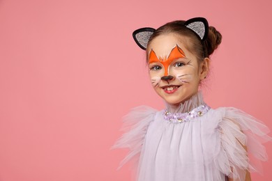 Cute girl with painted face and ears as cat on pink background, space for text