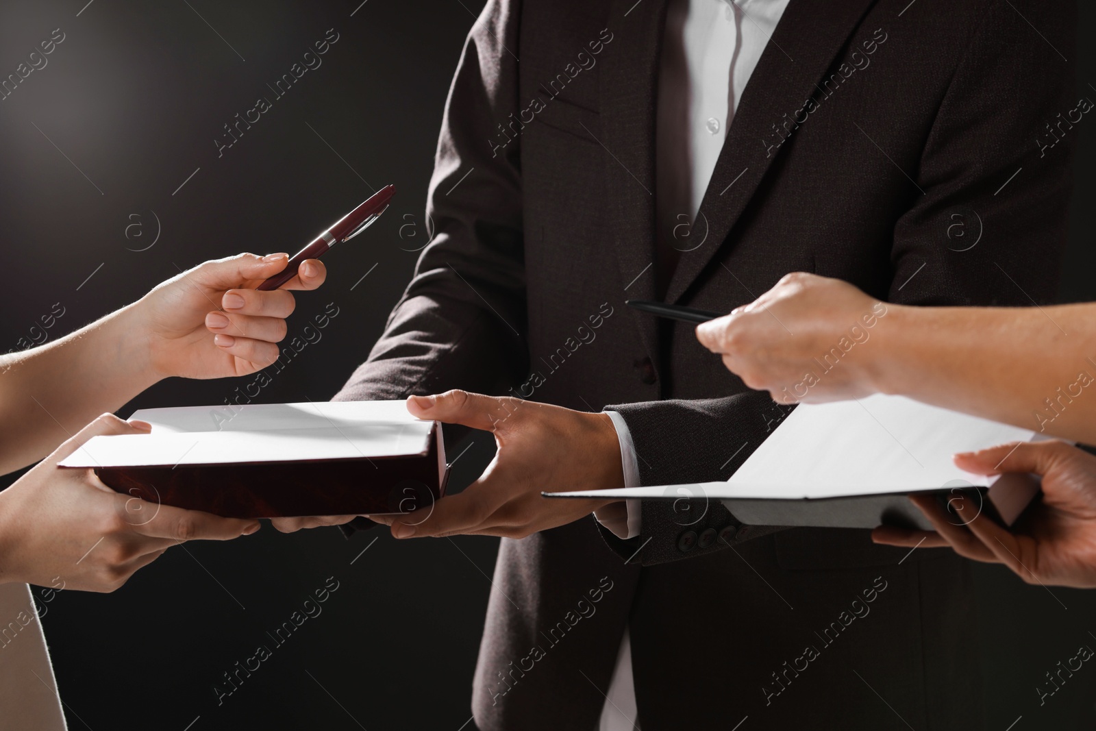 Photo of Writer signing autograph in book on black background, closeup