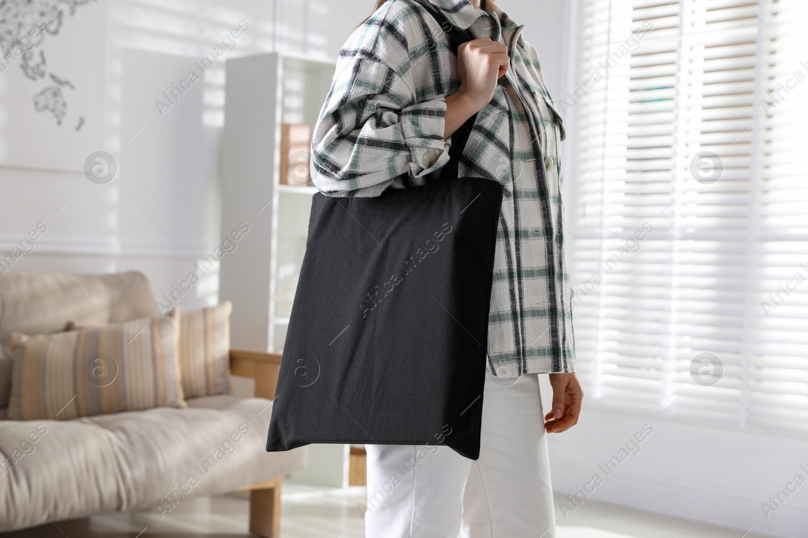 Photo of Woman with blank black shopper bag indoors, closeup. Mockup for design