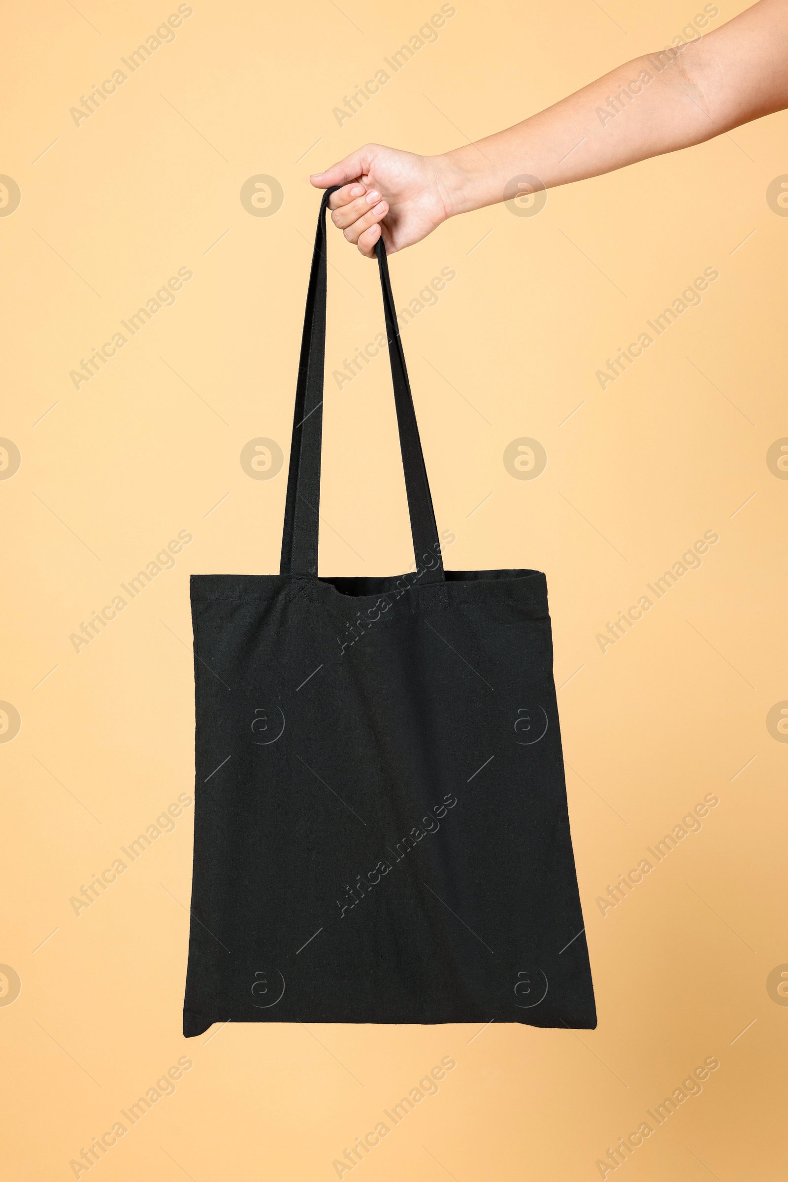 Photo of Woman with blank black shopper bag on color background, closeup. Mockup for design