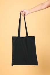 Photo of Woman with blank black shopper bag on color background, closeup. Mockup for design