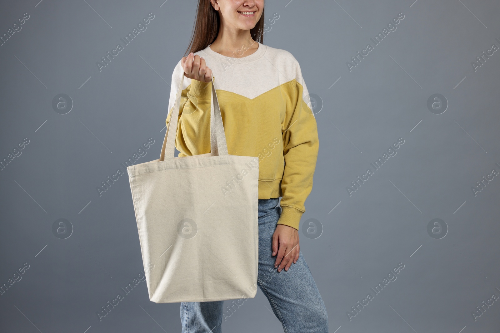 Photo of Woman with blank shopper bag on grey background, closeup. Mockup for design