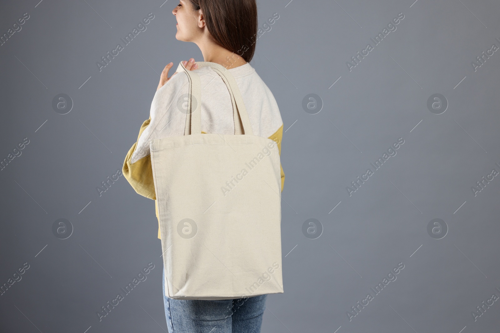 Photo of Woman with blank shopper bag on grey background, back view. Mockup for design