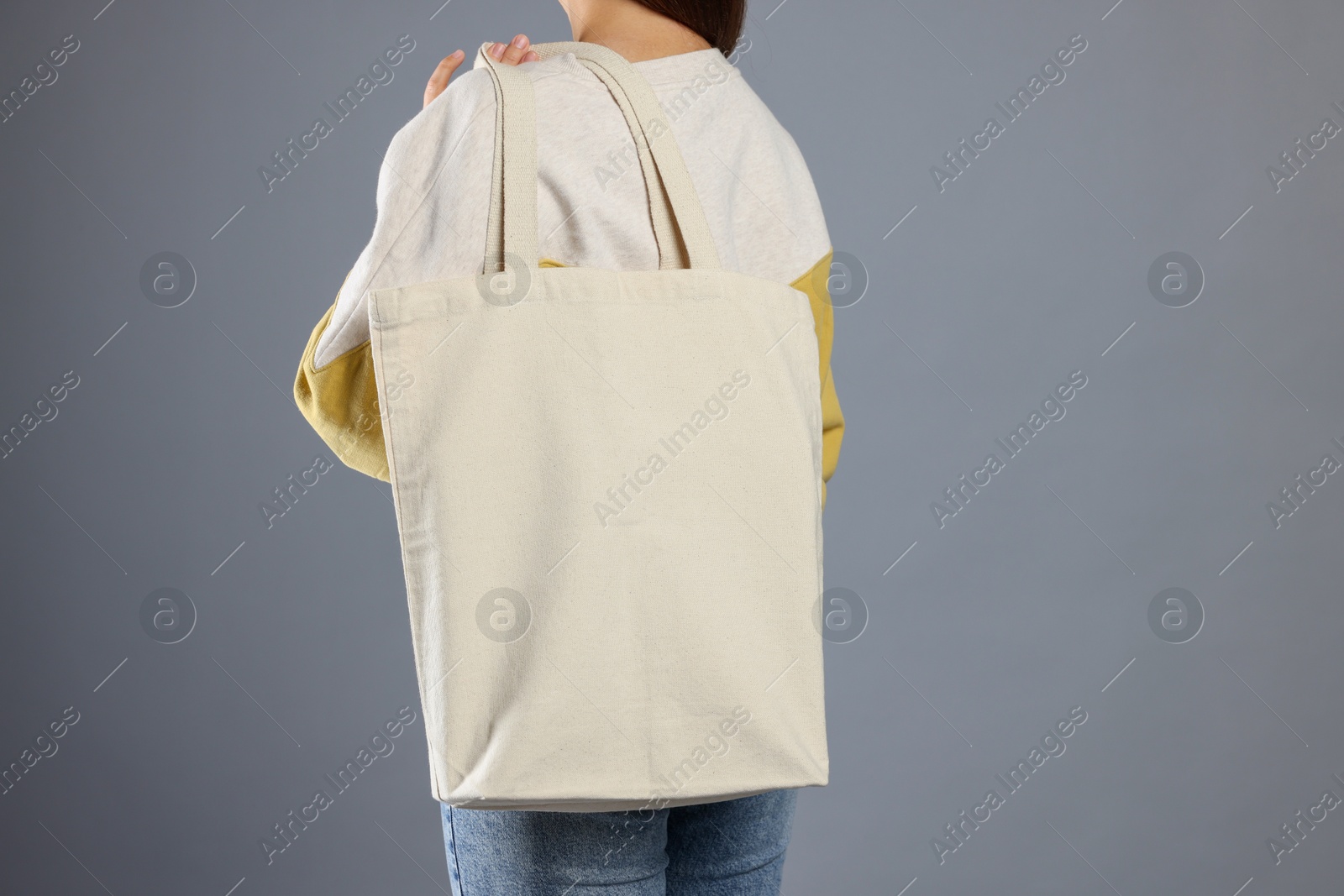 Photo of Woman with blank shopper bag on grey background, back view. Mockup for design