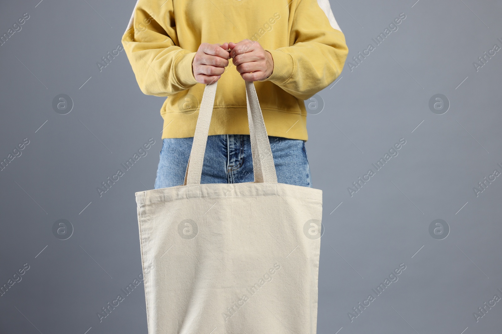 Photo of Woman with blank shopper bag on grey background, closeup. Mockup for design