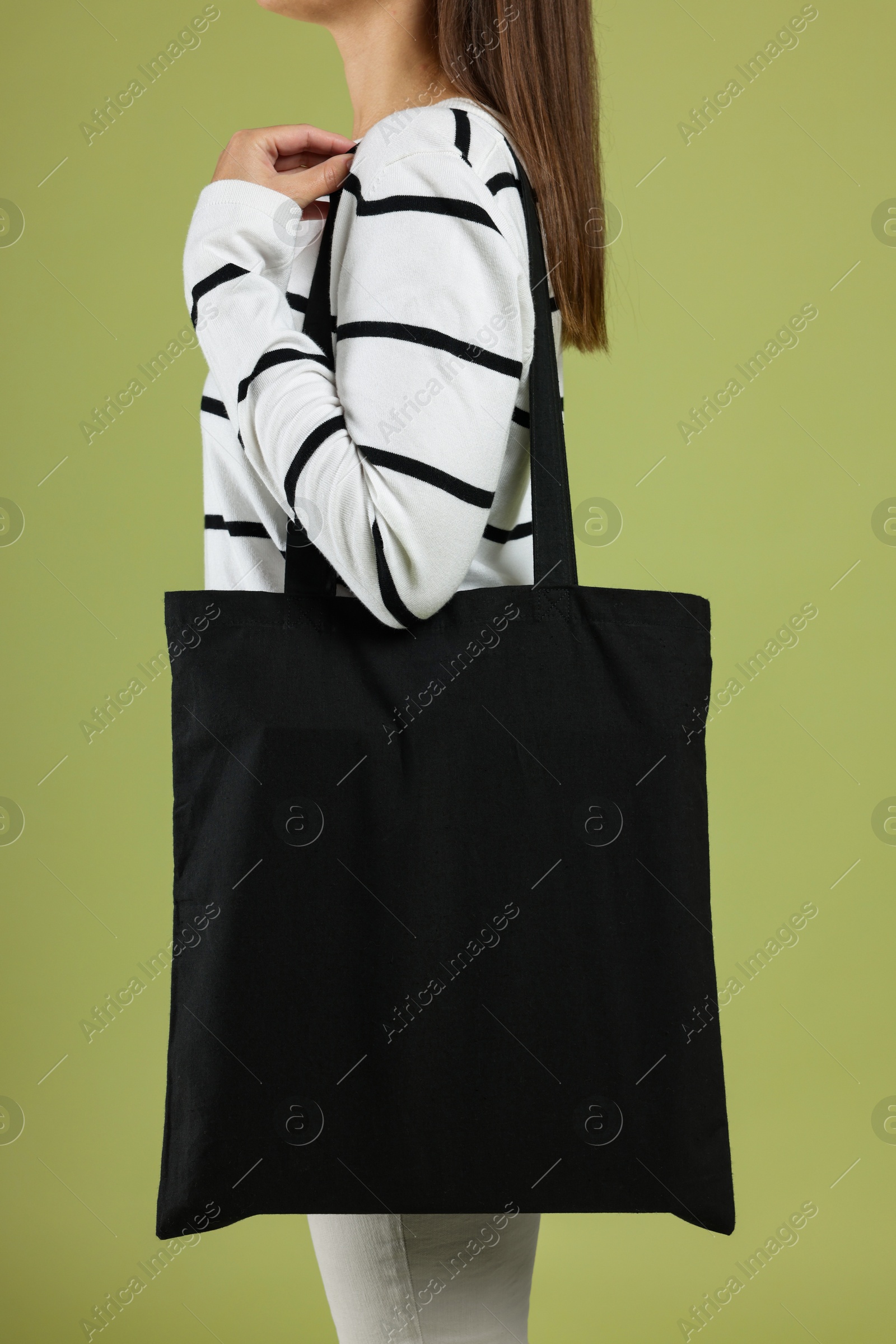 Photo of Woman with blank black shopper bag on color background, closeup. Mockup for design