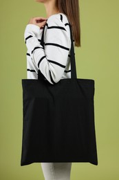 Woman with blank black shopper bag on color background, closeup. Mockup for design