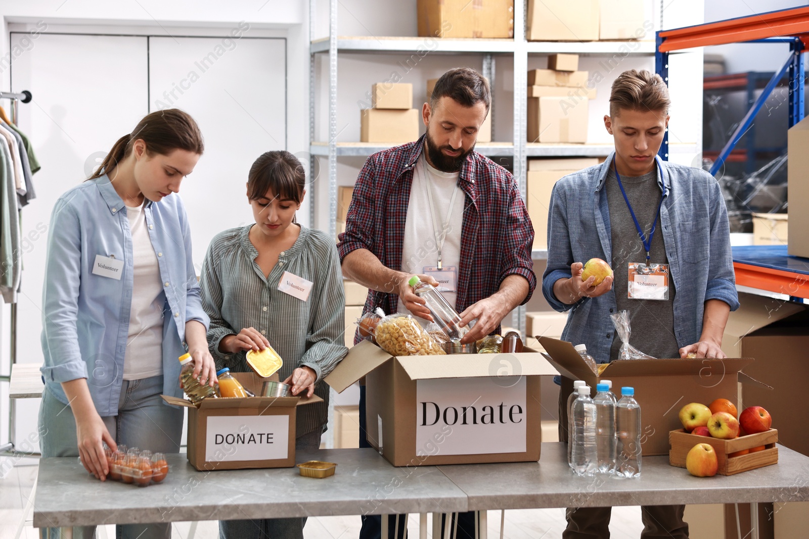 Photo of Group of volunteers packing food donations at table indoors